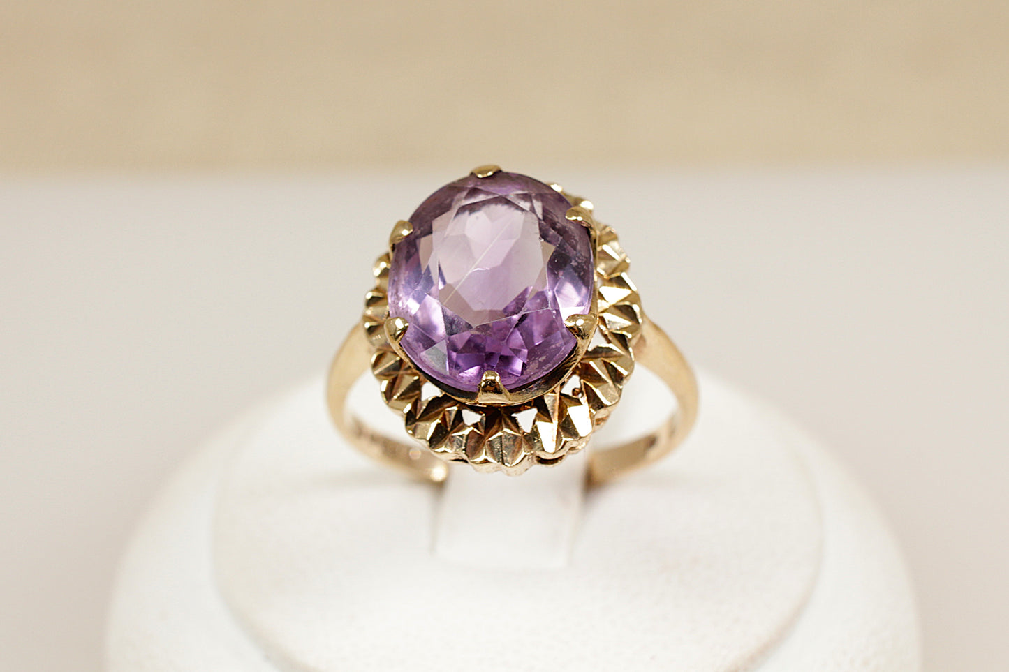 A vintage 9ct gold amethyst solitaire ring with a large oval-cut purple amethyst center stone, set in an ornate crown-style setting with intricate goldwork.