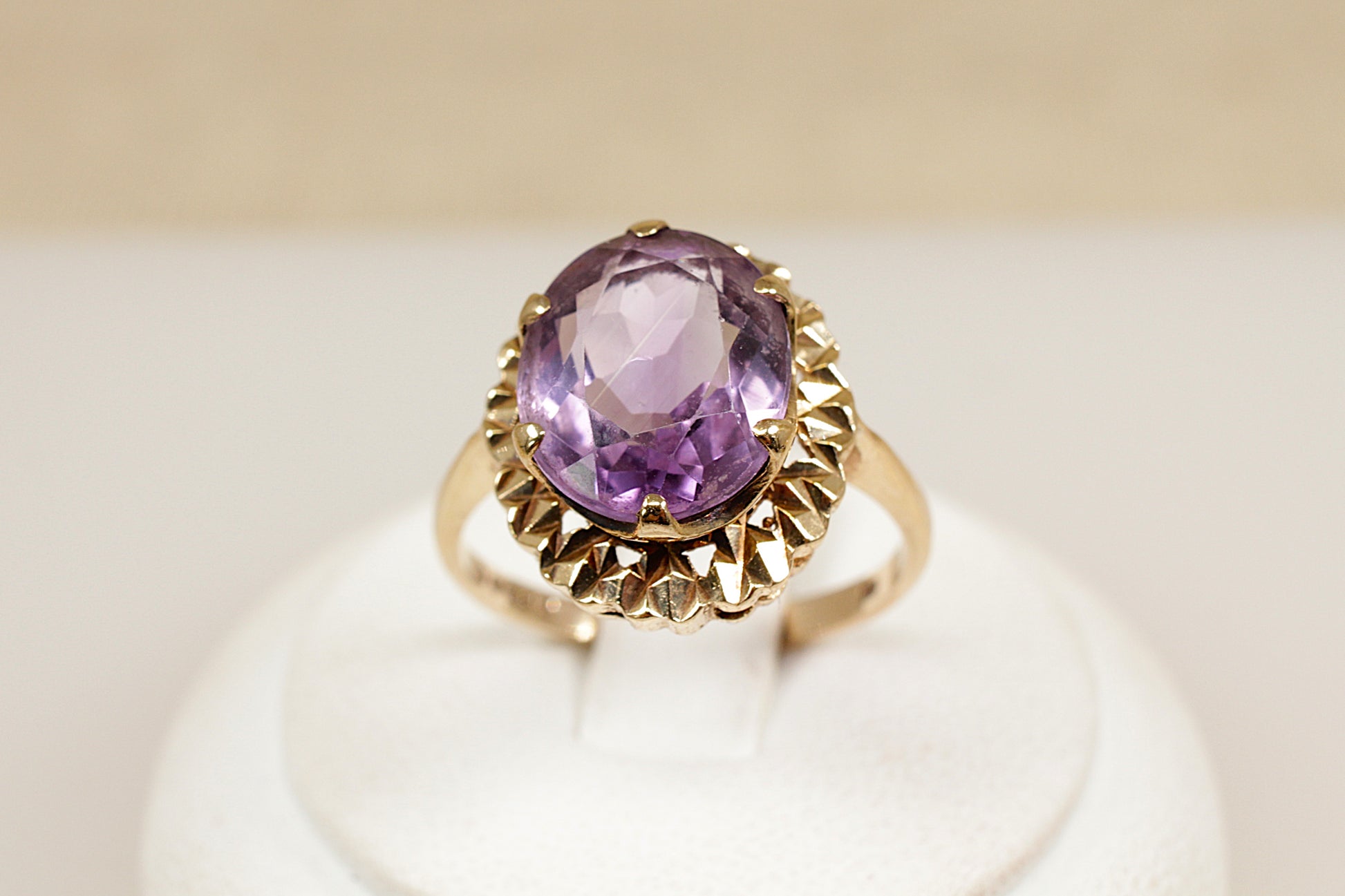 A vintage 9ct gold amethyst solitaire ring with a large oval-cut purple amethyst center stone, set in an ornate crown-style setting with intricate goldwork.