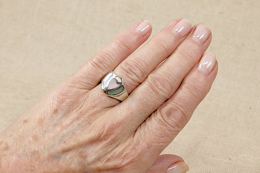 A sterling silver ring with pink and blue mother of pearl inlay in the shape of two hearts, displayed on a hand.