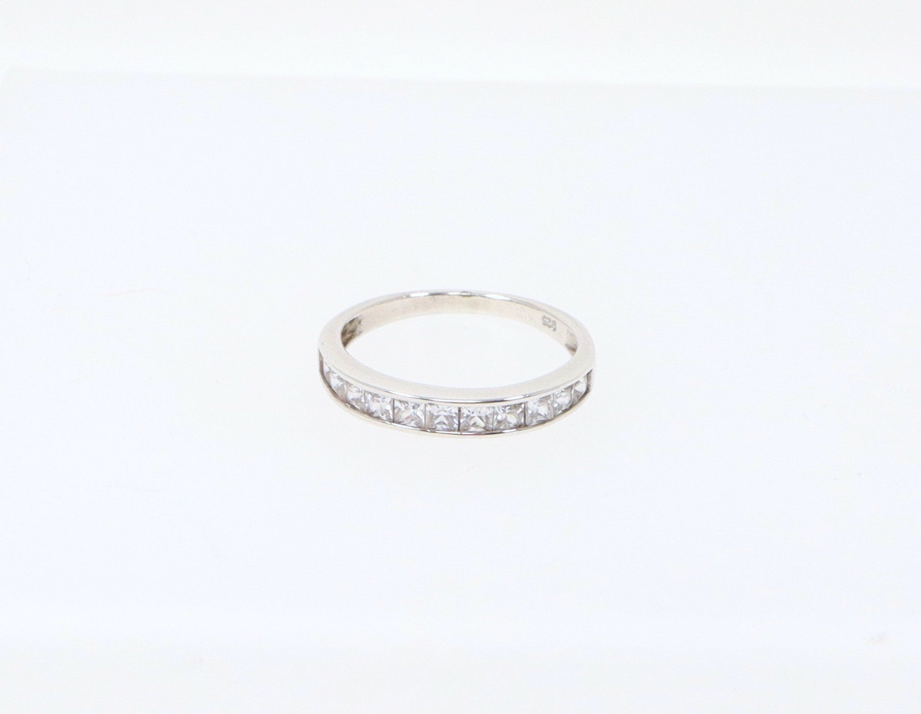 A sterling silver half eternity ring with 11 channel set princess cut cubic zirconia gemstones. Cubic Zirconia has all the style and elegance of a real diamonds, looks just like the genuine item, add some affordable sparkle. The ring is stamped 925 inside the band for sterling silver. UK finger size R.