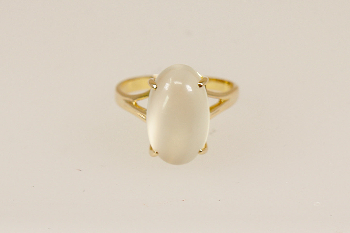 A truly enchanting 14ct Gold solitaire ring, showcasing a large, luminous cabochon-cut Moonstone that glows with soft, ethereal shimmer. The gemstone is held securely by four bold claws, rising from a basket-style setting that adds depth and classic elegance to the design, Inside the band, it is clearly stamped 585, confirming its 14ct gold purity, UK Finger size: N.