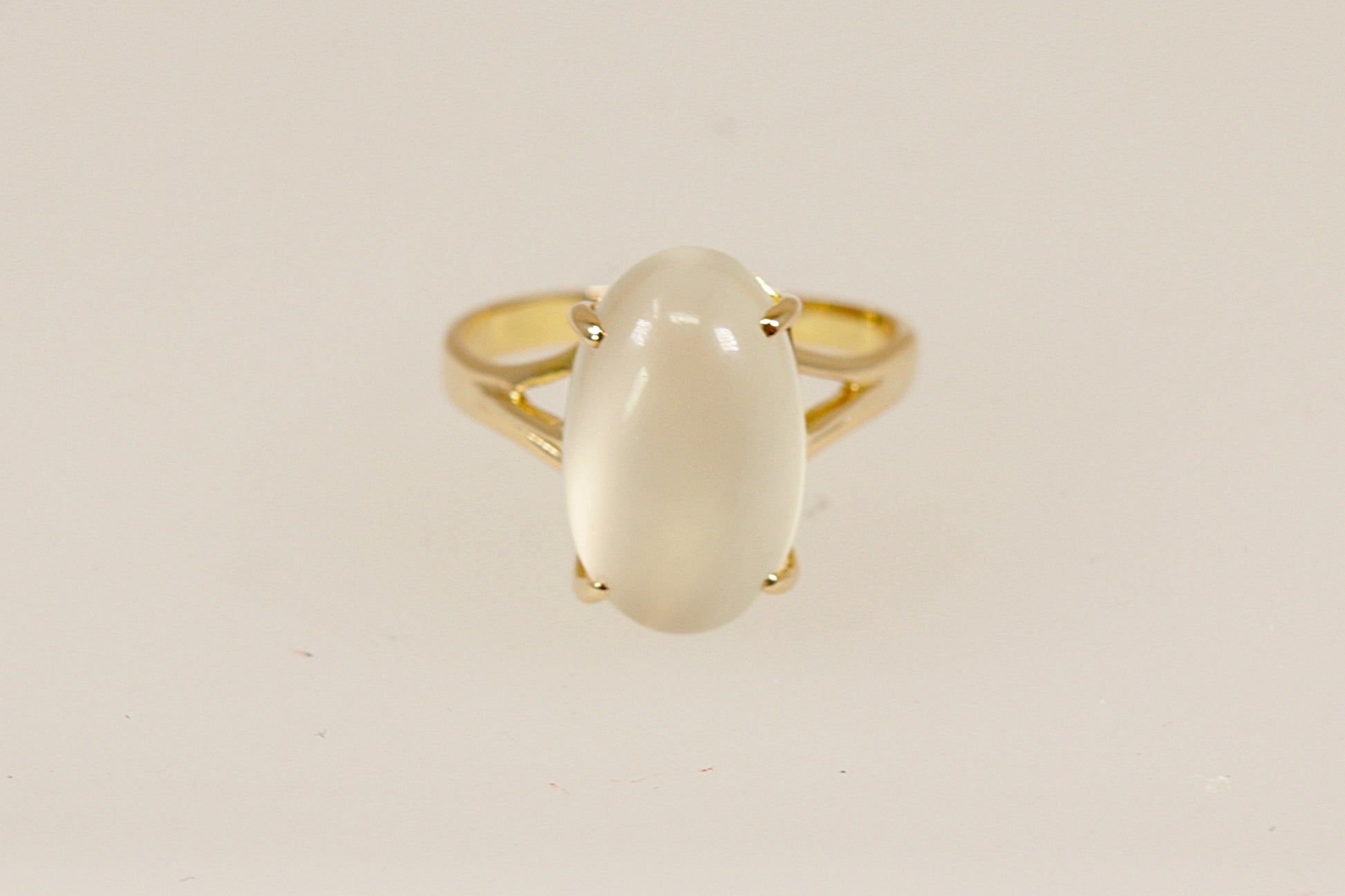 A truly enchanting 14ct Gold solitaire ring, showcasing a large, luminous cabochon-cut Moonstone that glows with soft, ethereal shimmer. The gemstone is held securely by four bold claws, rising from a basket-style setting that adds depth and classic elegance to the design, Inside the band, it is clearly stamped 585, confirming its 14ct gold purity, UK Finger size: N.