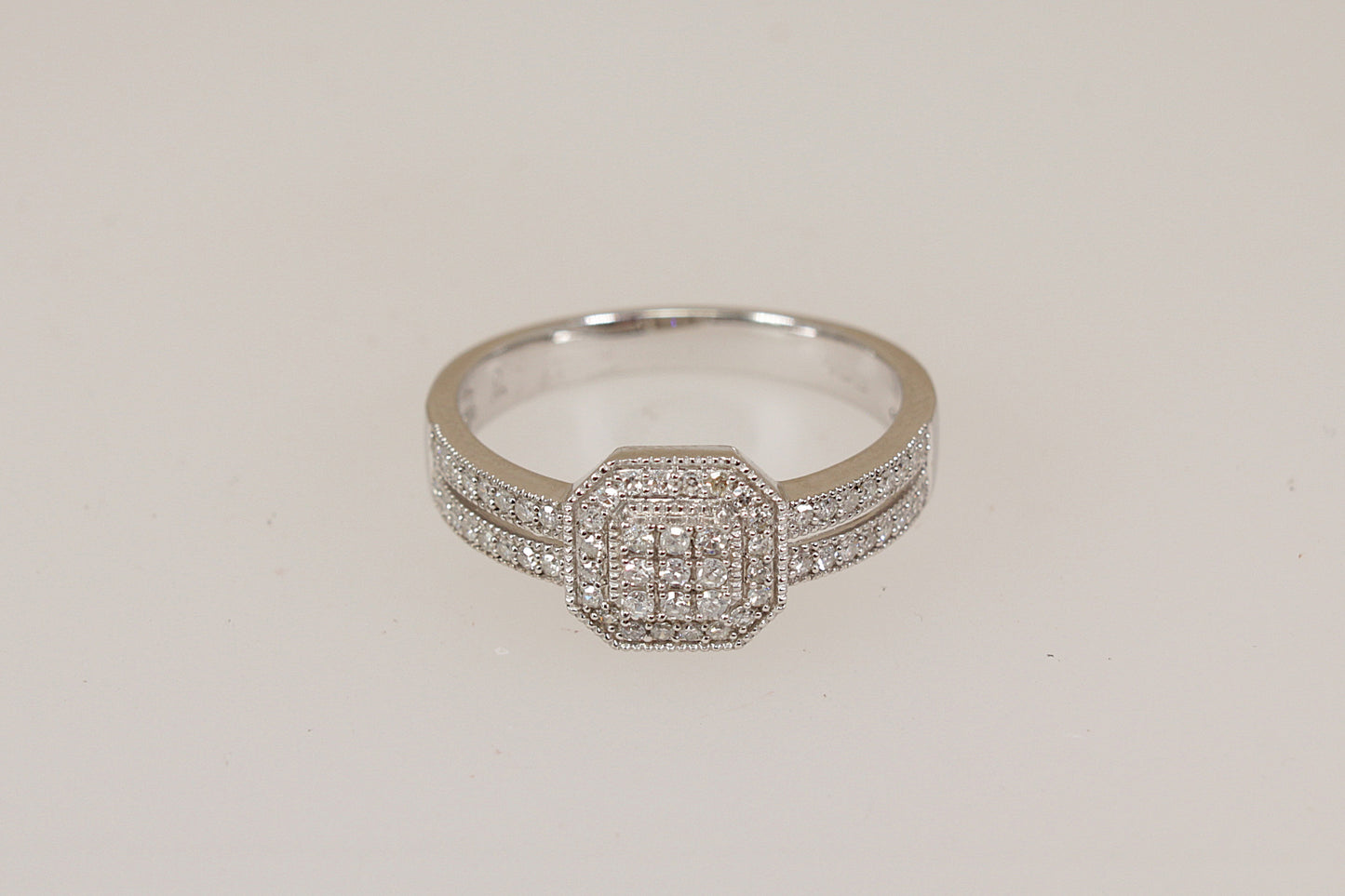 White gold diamond ring with diamond accents on a light beige background