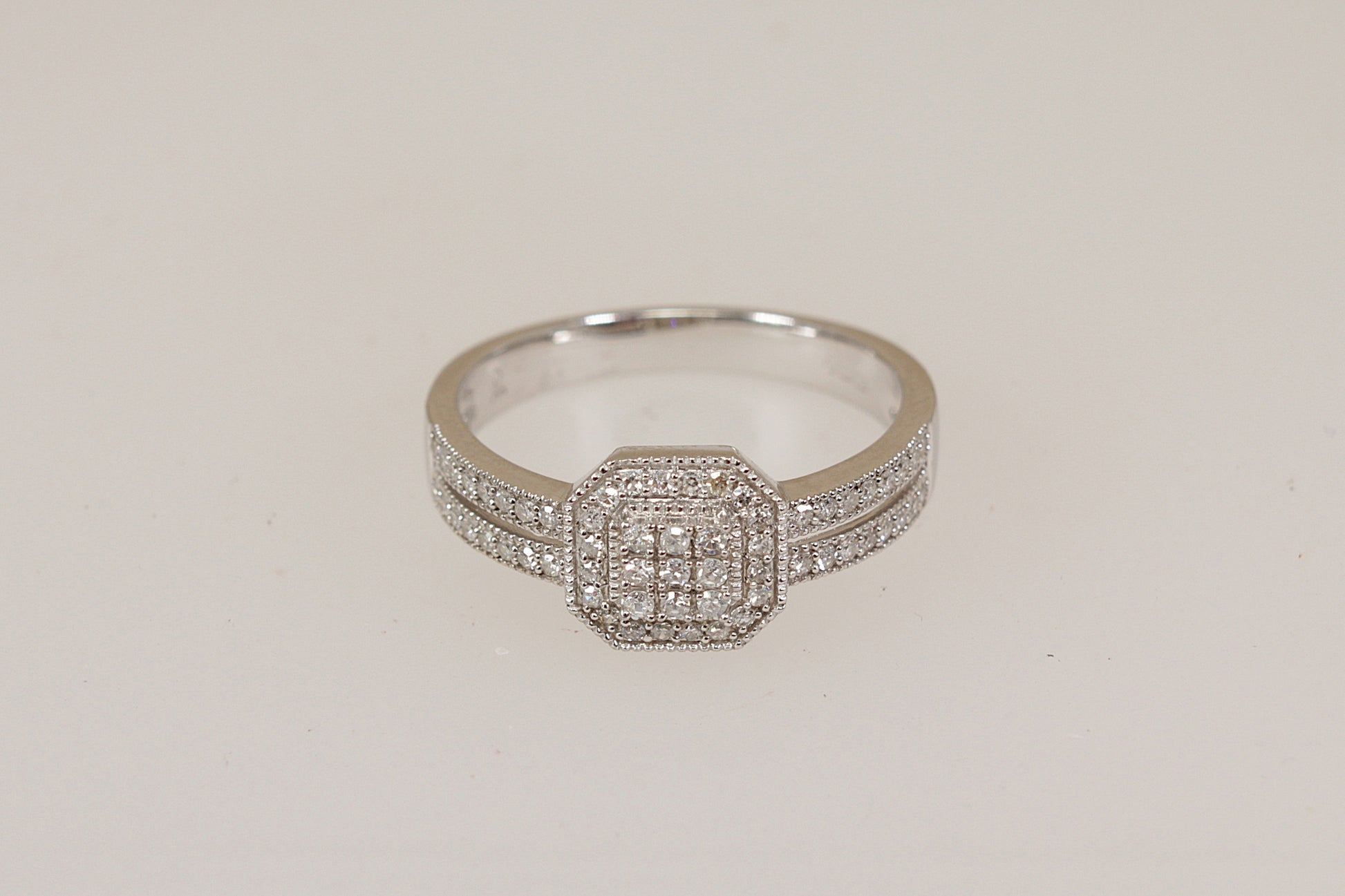 White gold diamond ring with diamond accents on a light beige background