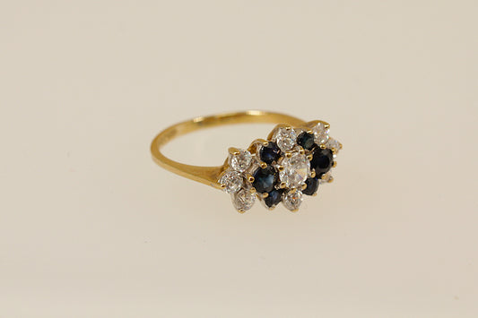 Gold ring with blue and white gemstones on a beige background