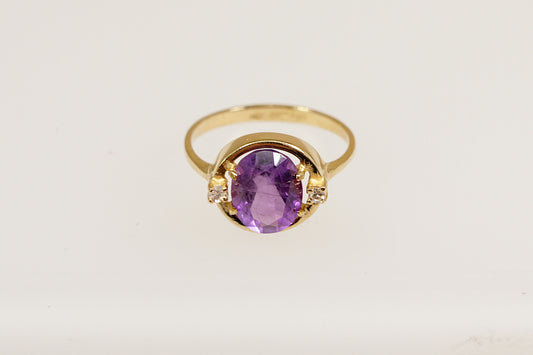 An 18ct yellow gold amethyst solitaire ring  the Amethyst is flanked a round cut diamond on each side, the ring is stamped 750 for 18ct gold, UK finger size  L.