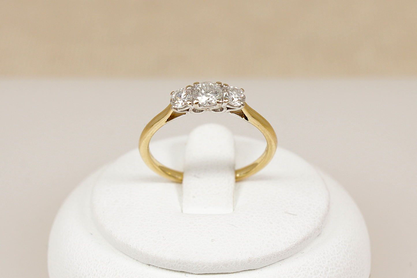 18ct yellow gold ring with diamonds on a white stand against a beige background