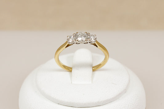 18ct yellow gold ring with diamonds on a white stand against a beige background