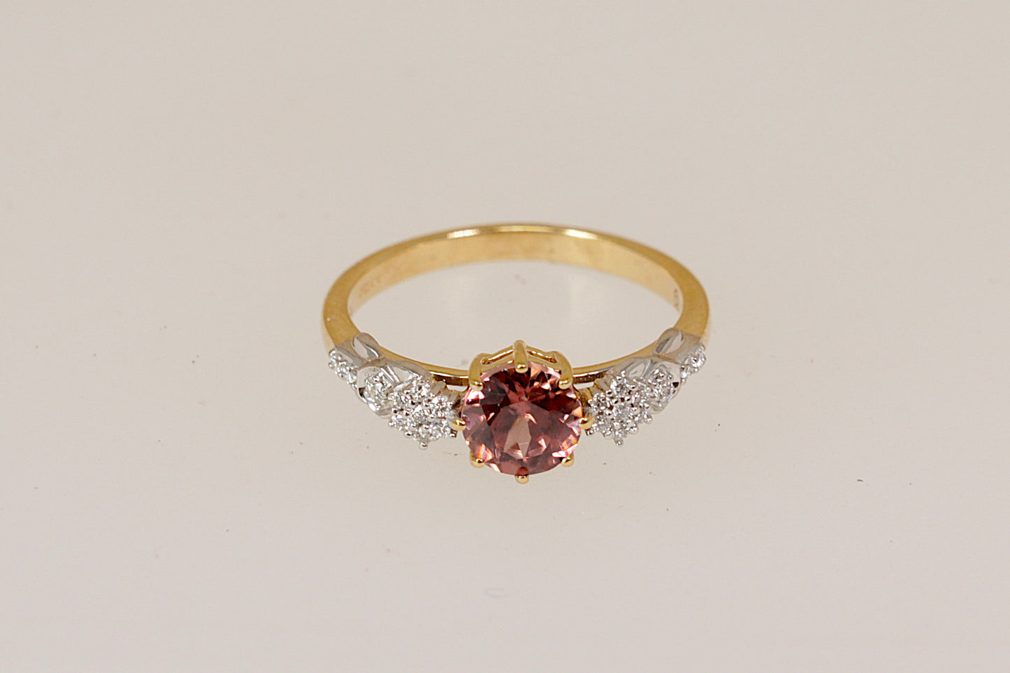 18ct Gold ring with a pink tourmaline and diamond gemstones on a light gray background
