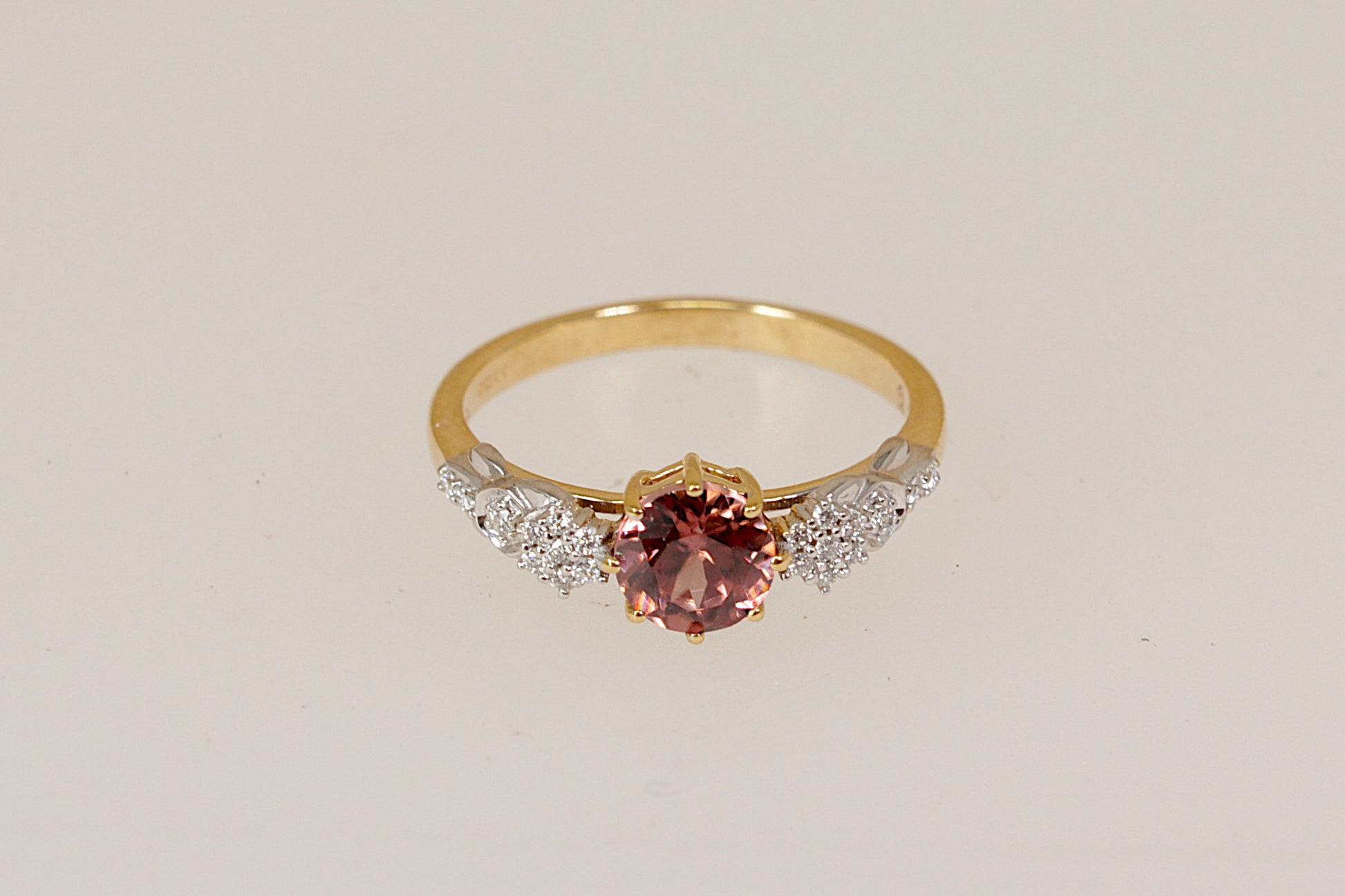 18ct Gold ring with a pink tourmaline and diamond gemstones on a light gray background