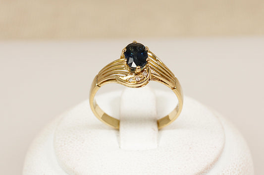18ct yellow gold sapphire and diamond solitaire ring, the centre rich blue sapphire is approximately 0.60 carat in weight with three diamonds top and bottom of the gemstone, UK finger size N.