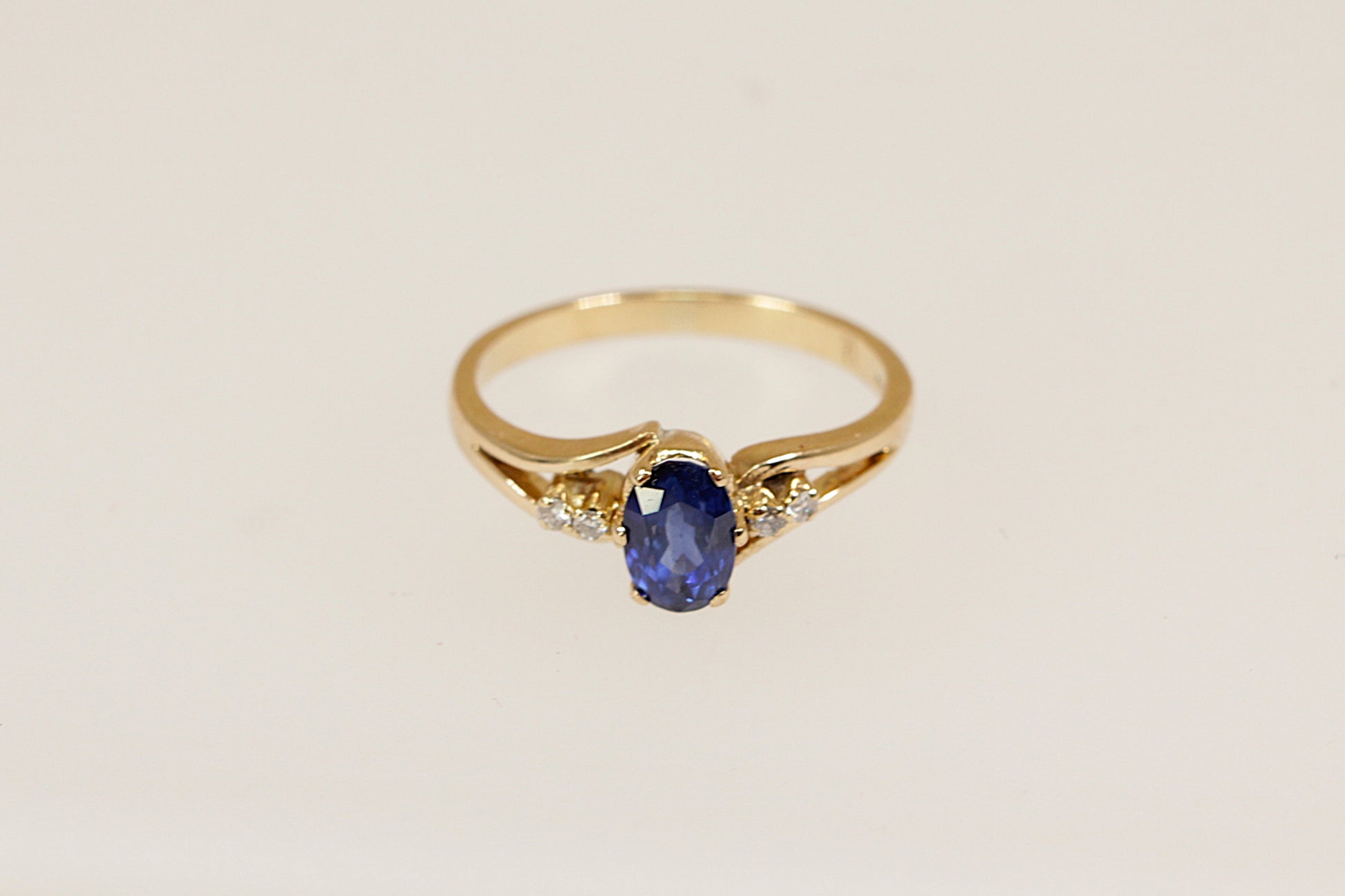 18ct yellow gold solitaire ring with a beautiful royal blue oval sapphire of approximately 0.50carat adorned by two round cut diamonds on each shoulder UK finger size L.