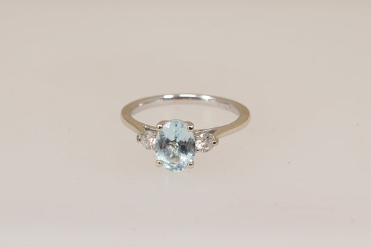 18ct white gold trilogy ring with a blue aquamarine and diamond  gemstones on a beige background