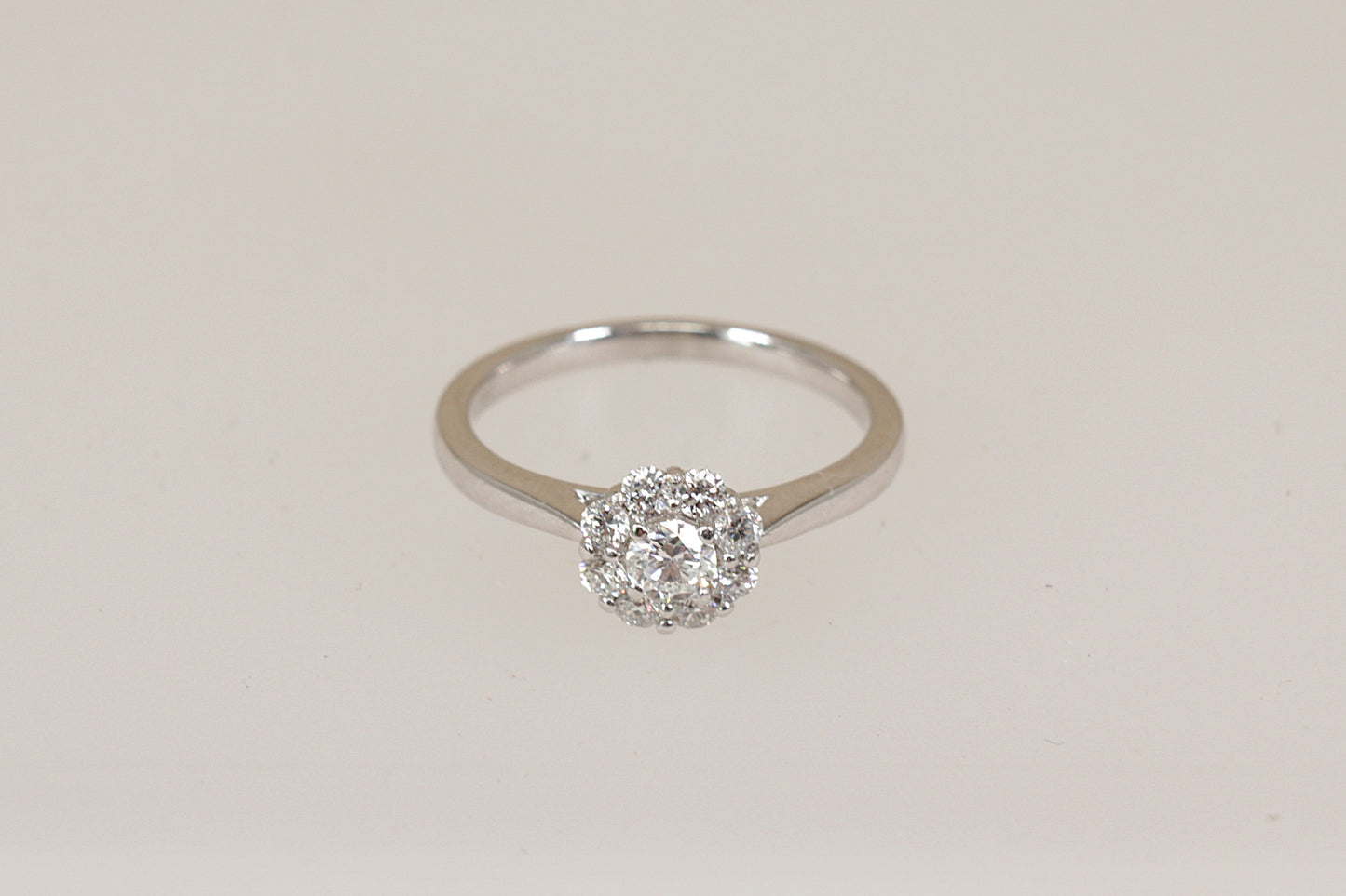 Certified Diamond daisy cluster ring on a light beige background