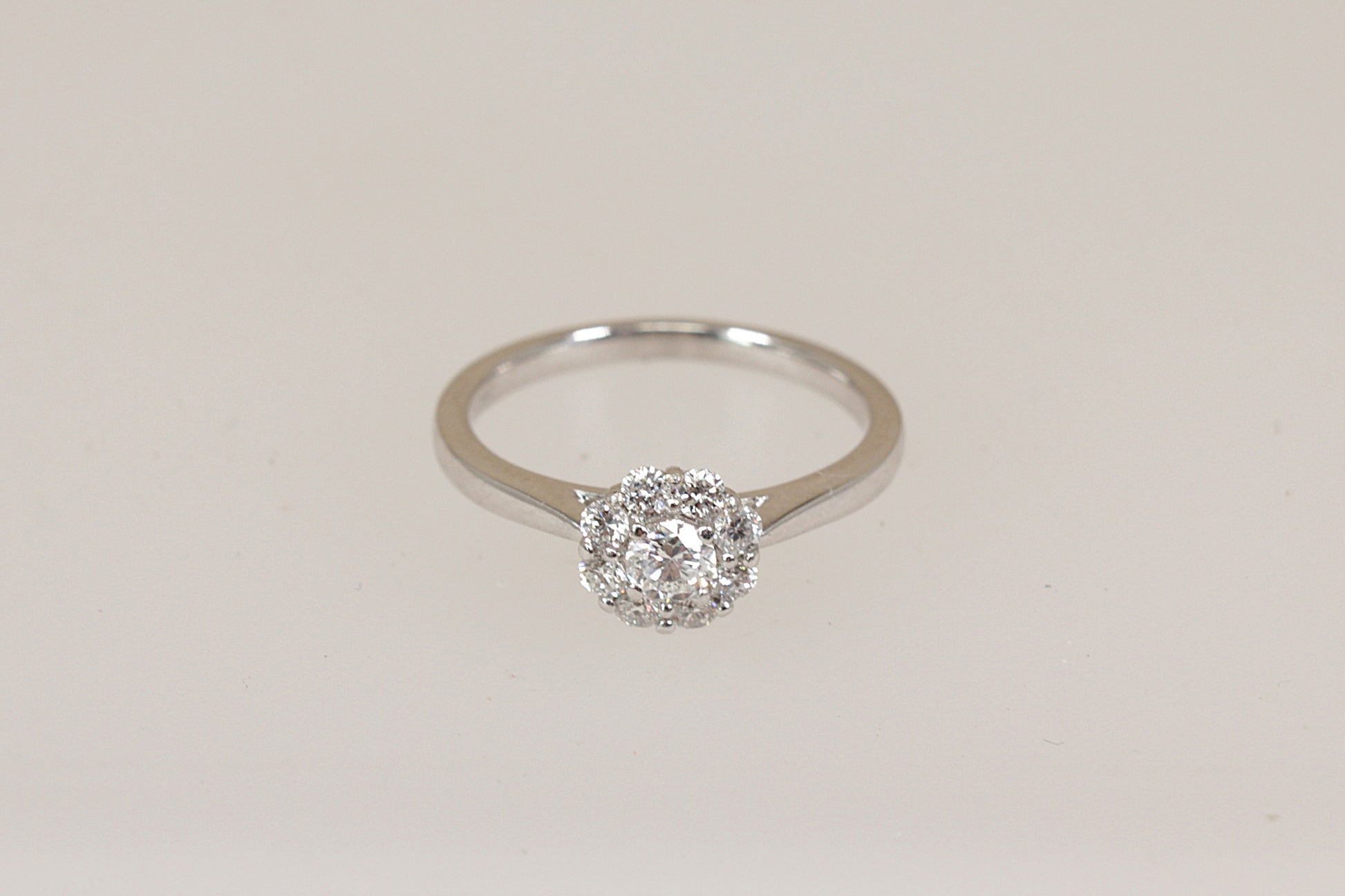 Certified Diamond daisy cluster ring on a light beige background