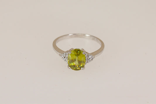 18ct white gold ring with a vibrant green Peridot gemstone with diamond accents on a beige background