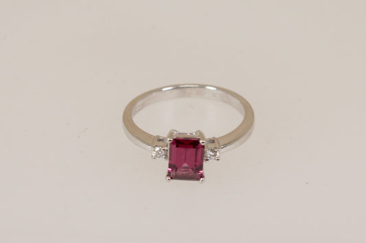 18ct white gold ring with a red rhodolite and diamond gemstones on a light beige background