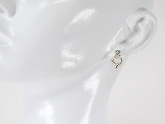 A pair of silver stud earrings in the shape of a petal, displayed on a mannequin ear.