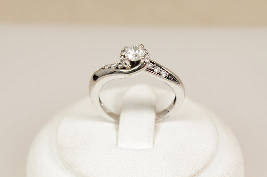 White gold diamond solitaire ring with  diamonds on the shoulders on a white cushion