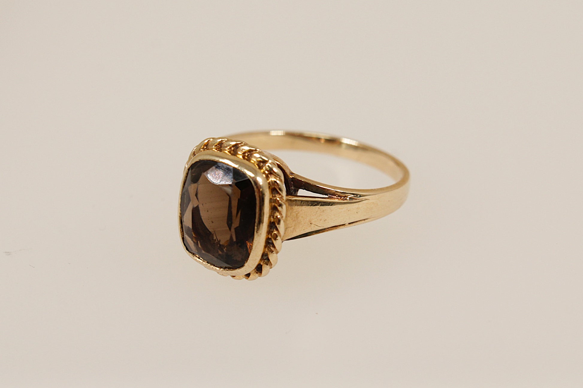 Gold ring with a smoky gemstone on a beige background