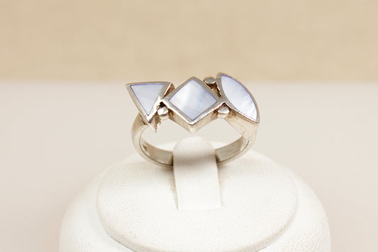 Silver mother of pearl ring with three triangular mop gemstones on a beige background
