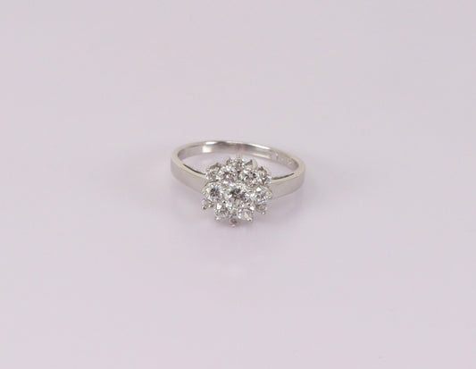 A silver cluster ring with cubic zirconia stones arranged in a daisy pattern, displayed against a white background.