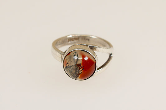A vintage silver ring with a round Moss Agate stone displaying red, green, and brown colors, on a white background.