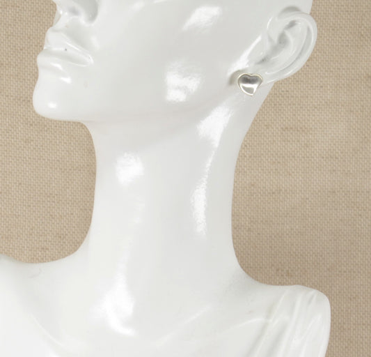 A pair of silver heart stud earrings displayed on a mannequin head.