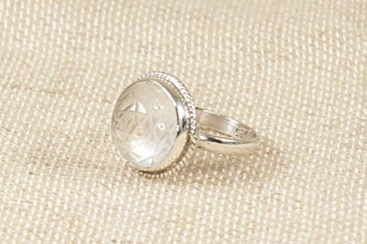 A sterling silver statement ring with a clear round cabochon quartz gemstone etched with star decoration stamped 925 for sterling silver, UK finger size O. 