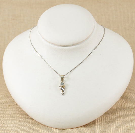 A silver pendant necklace with a round blue topaz set in a Celtic knot design, displayed on a white mannequin.