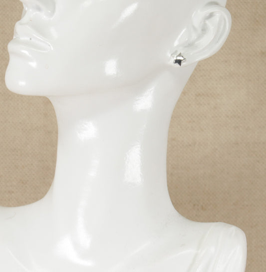 A pair of silver stud earrings in the shape of a 5 pointed star displayed on a mannequin head.