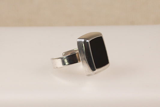 An adjustable silver ring with a black onyx center stone, displayed against a neutral background.