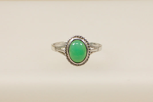 An oval cabochon chrysoprase gemstone set in a sterling silver ring with hallmarks visible inside the band.