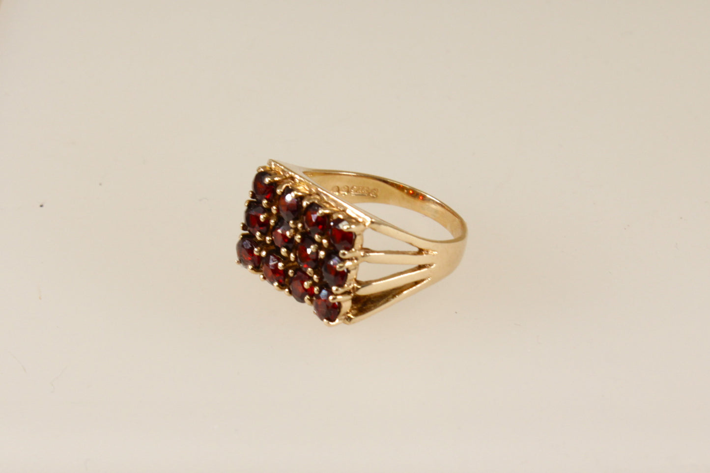 A 9ct gold ring with a cluster of round garnets set in a rectangular head with claw-shaped shoulders.