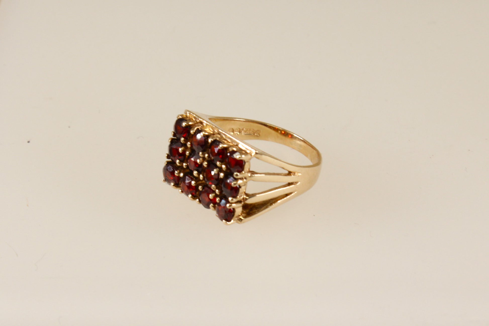 A 9ct gold ring with a cluster of round garnets set in a rectangular head with claw-shaped shoulders.