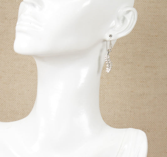 A pair of sterling silver earrings in the shape of a fern leaf on a mannequin head.