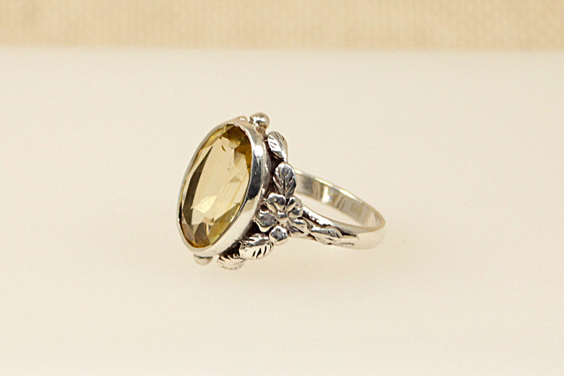 A vintage silver ring with a large oval citrine stone in an Art Nouveau style setting, featuring floral designs.