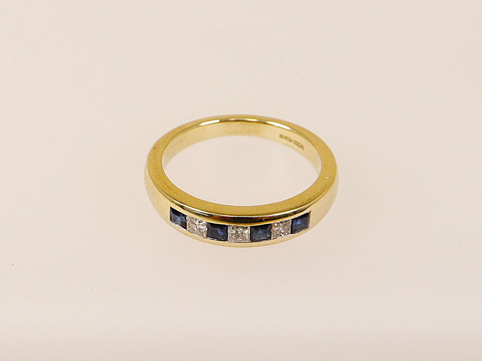 A 9ct gold band ring with channel-set blue sapphires and princess-cut diamonds