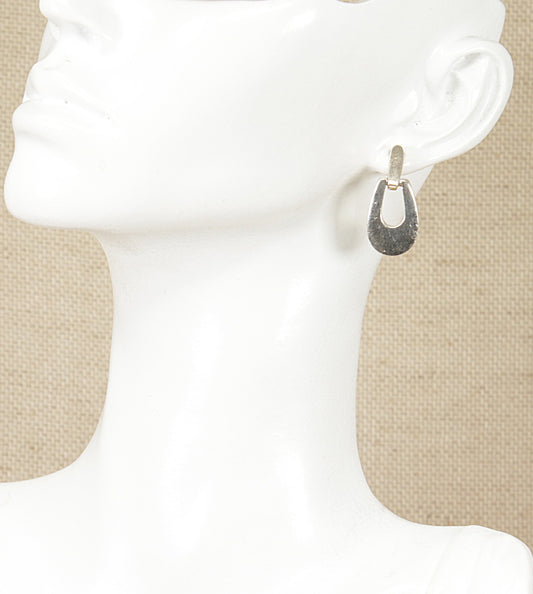 A pair of silver drop earrings displayed on a mannequin head.