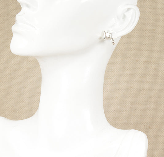 A pair of silver cubic zirconia stud earrings displayed on a mannequin head.
