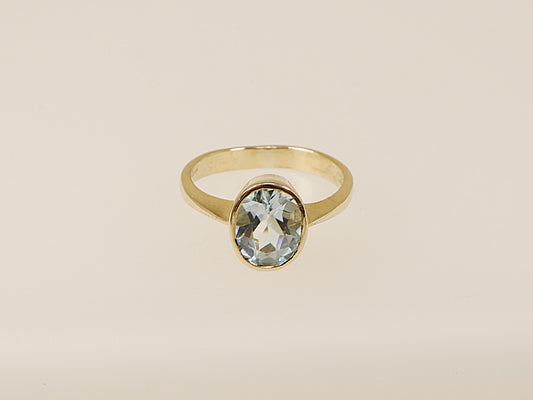 A vintage 9ct gold solitaire ring with an oval-cut blue topaz gemstone.