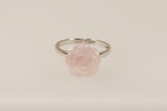 A silver ring with a carved pink rose as the central stone, displayed against a white background.