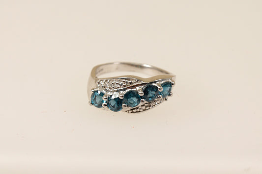 A sterling silver ring with five round blue topaz gemstones set across the band in a graceful curve with claw settings.
