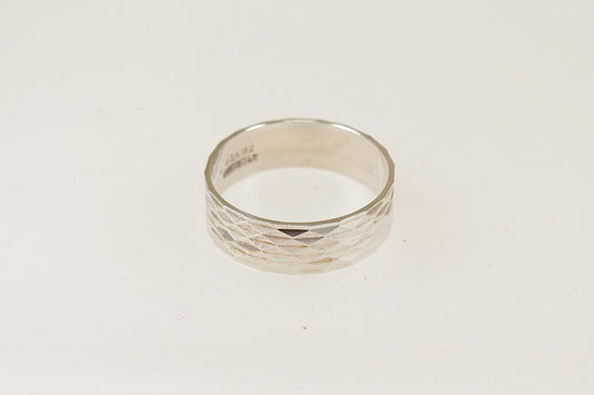 A silver band ring with an engine turned pattern, displayed against a white background.