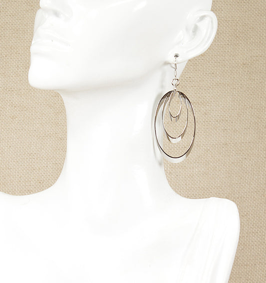 A pair of silver drop earrings with a trio of oblong rings on a mannequin head.