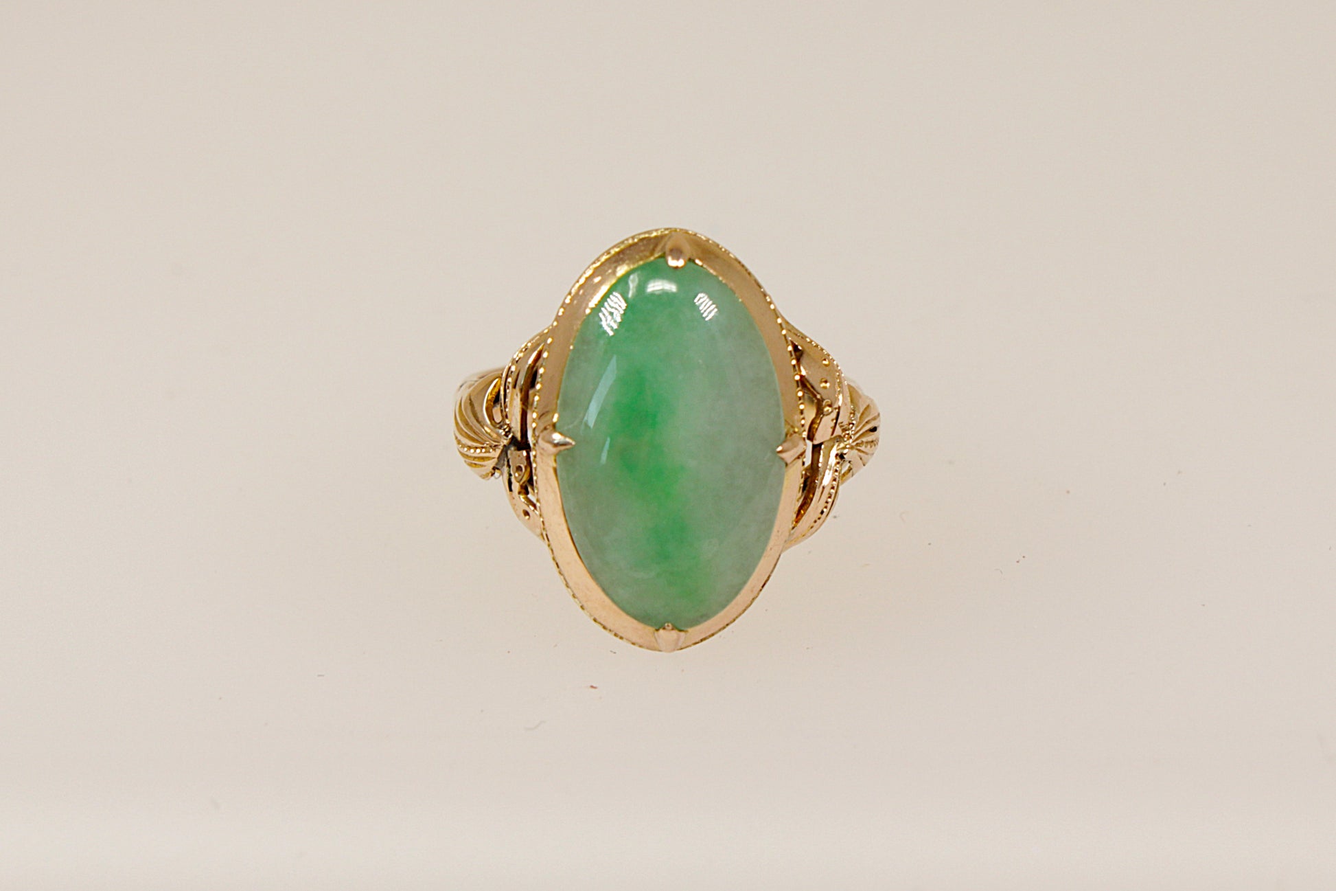 An oval-shaped jade cabochon ring set in a 14ct gold band with nature-inspired handcrafted goldwork.