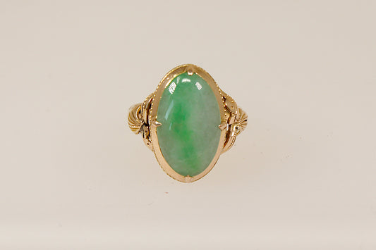 An oval-shaped jade cabochon ring set in a 14ct gold band with nature-inspired handcrafted goldwork.