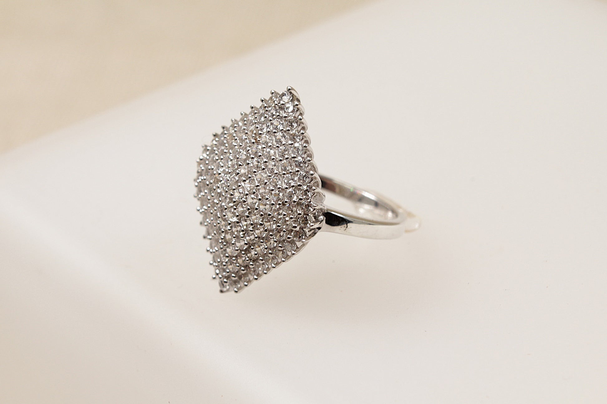 A silver cluster statement ring with a marquise shape and a pave set of white topaz gemstones on a white background.