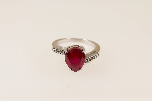 A sterling silver pear shaped ruby solitaire with white topaz accents on each shoulder, Stamped 925 for sterling silver and the makers mark ‘TGGC’ for The Genuine Gemstone Company, UK finger size J.