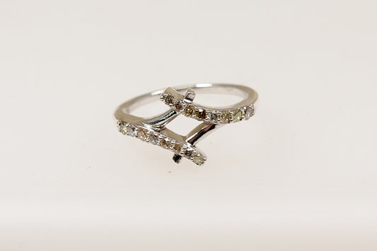 A silver diamond ring with two crossover bands, featuring claw set diamond gemstones on a white background.